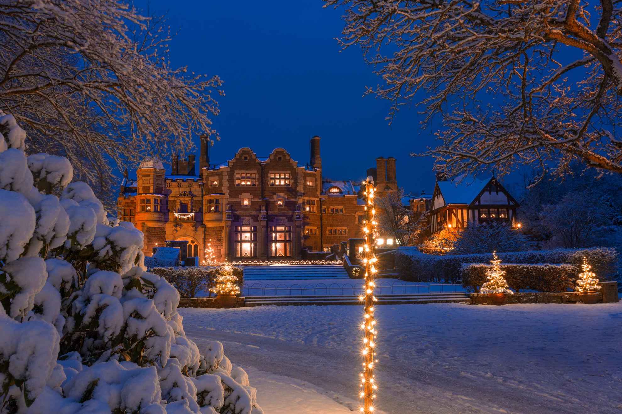 Ein schneebedecktes Schloss und Weihnachtsbeleuchtung in der Abenddämmerung.