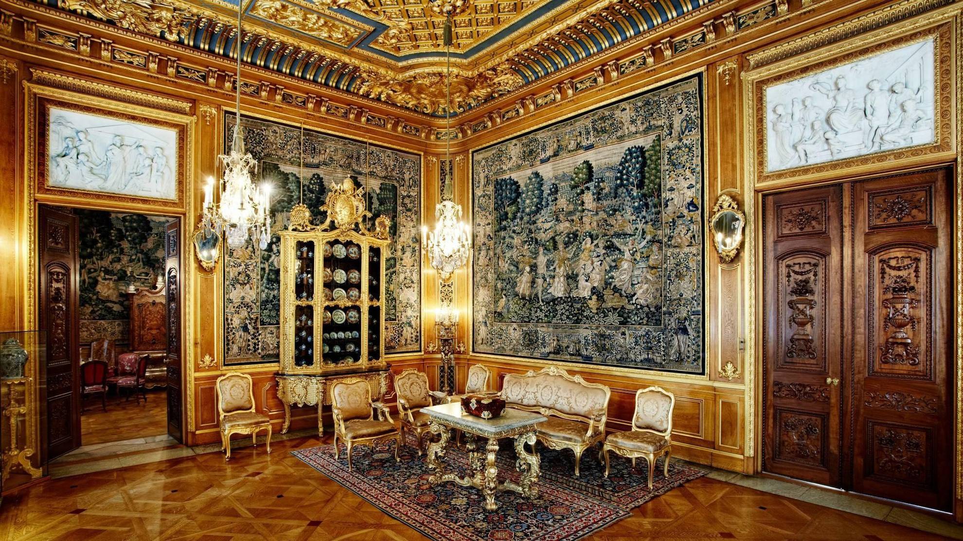 The luxurious, golden sitting room of Hallwyl house; with large paintings, golden furniture and chandeliers.