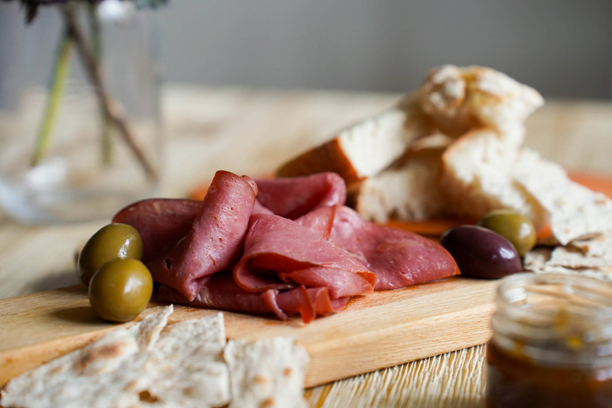 Eine Holzplatte mit Oliven, Brot und geräuchertem Rentierfleisch.