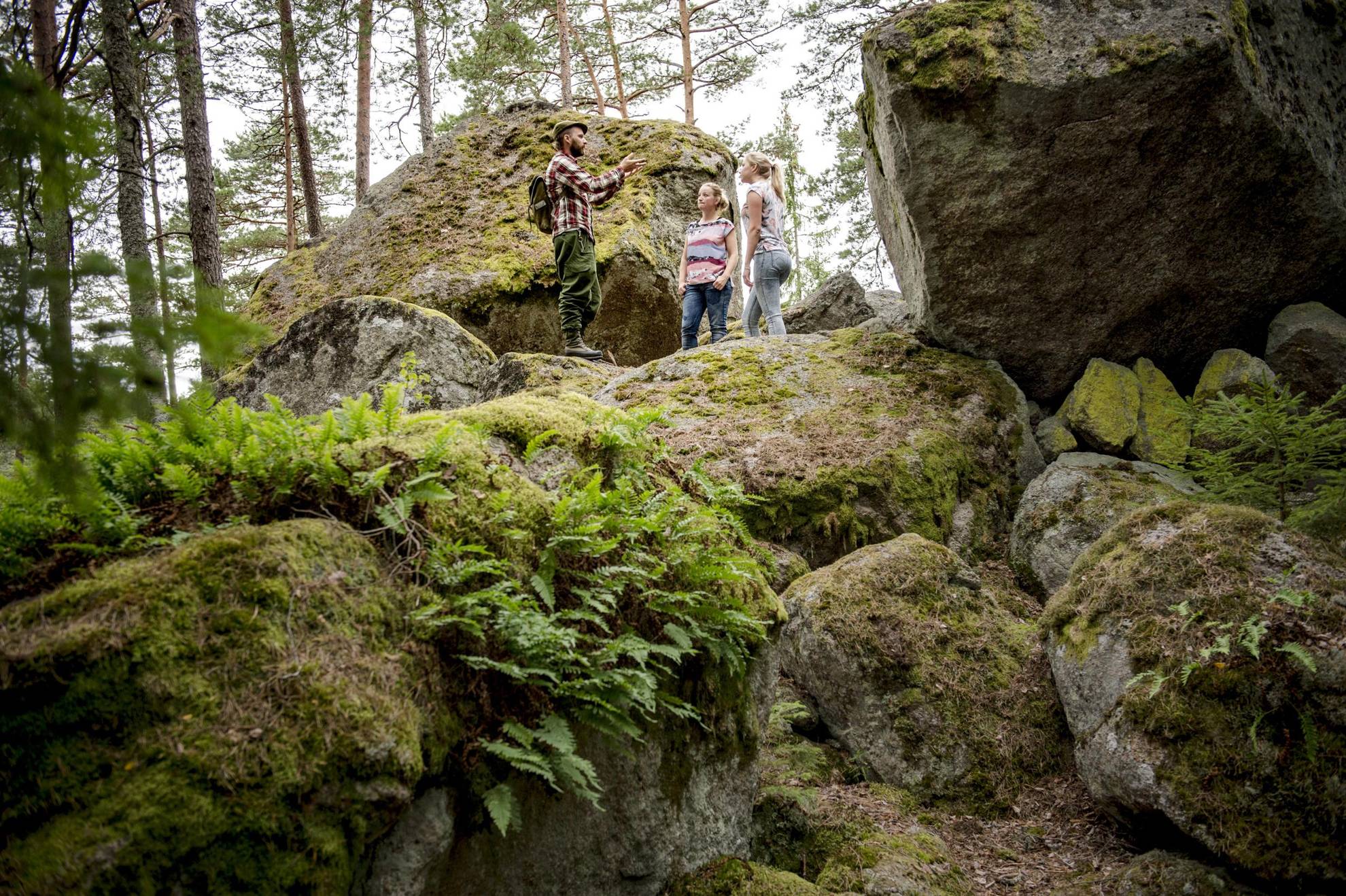 Zwei Frauen hören einem Guide zu, während sie in einem Wald stehen.