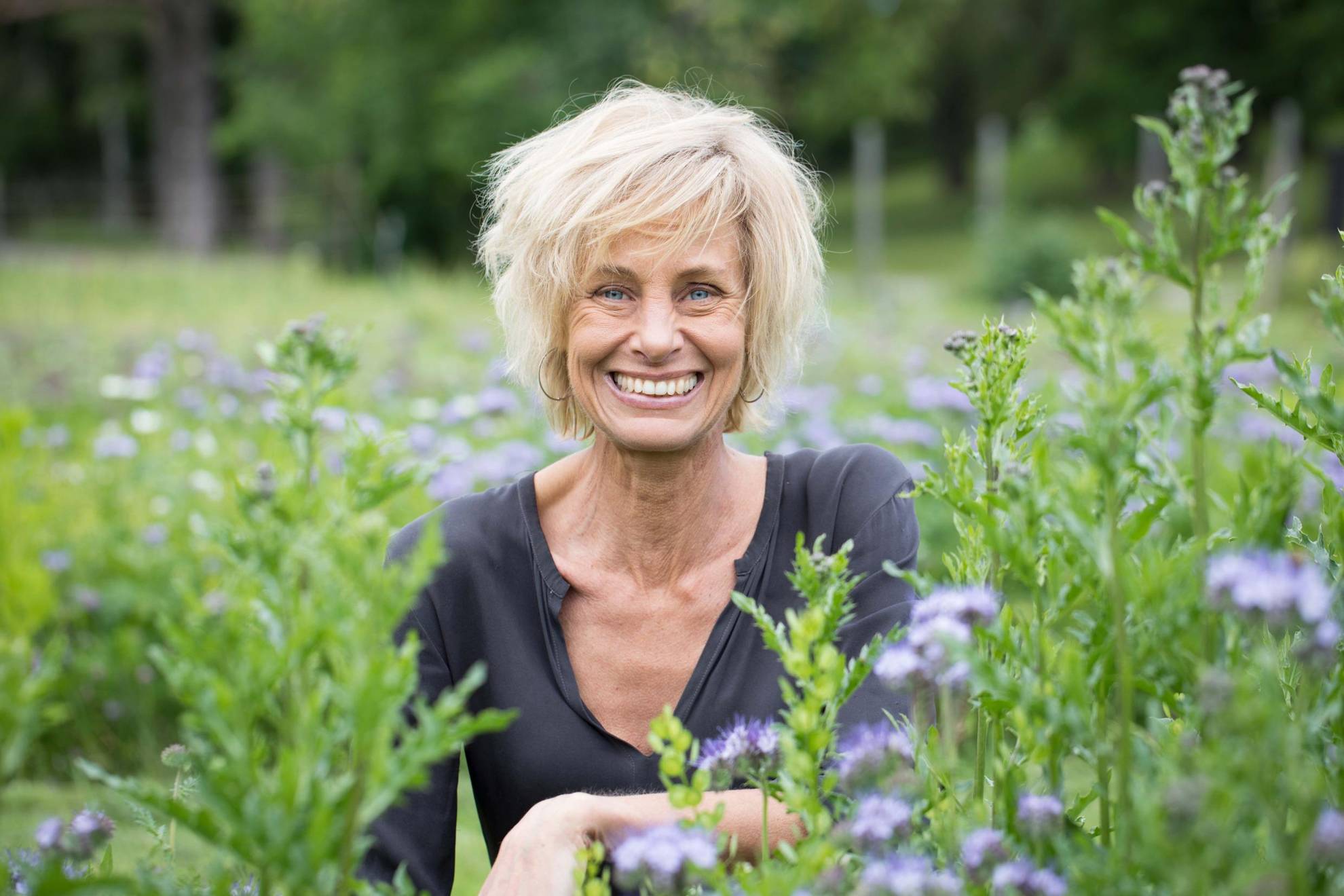 Ein Porträt von Lisen Sundgren in der Natur, umgeben von Grün. Sie lächelt in die Kamera.