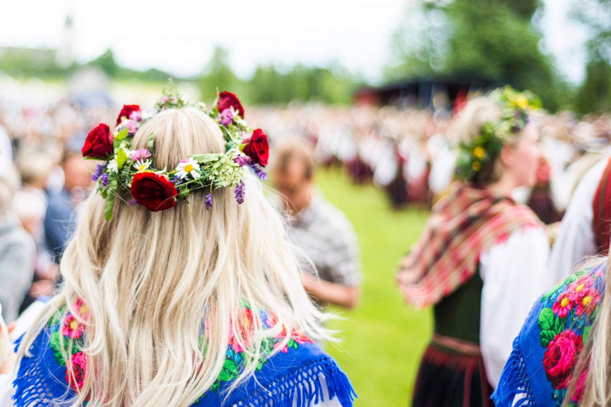 A crowd of people in Dalarna, some wearing Midsummer flower wreaths in their hair.