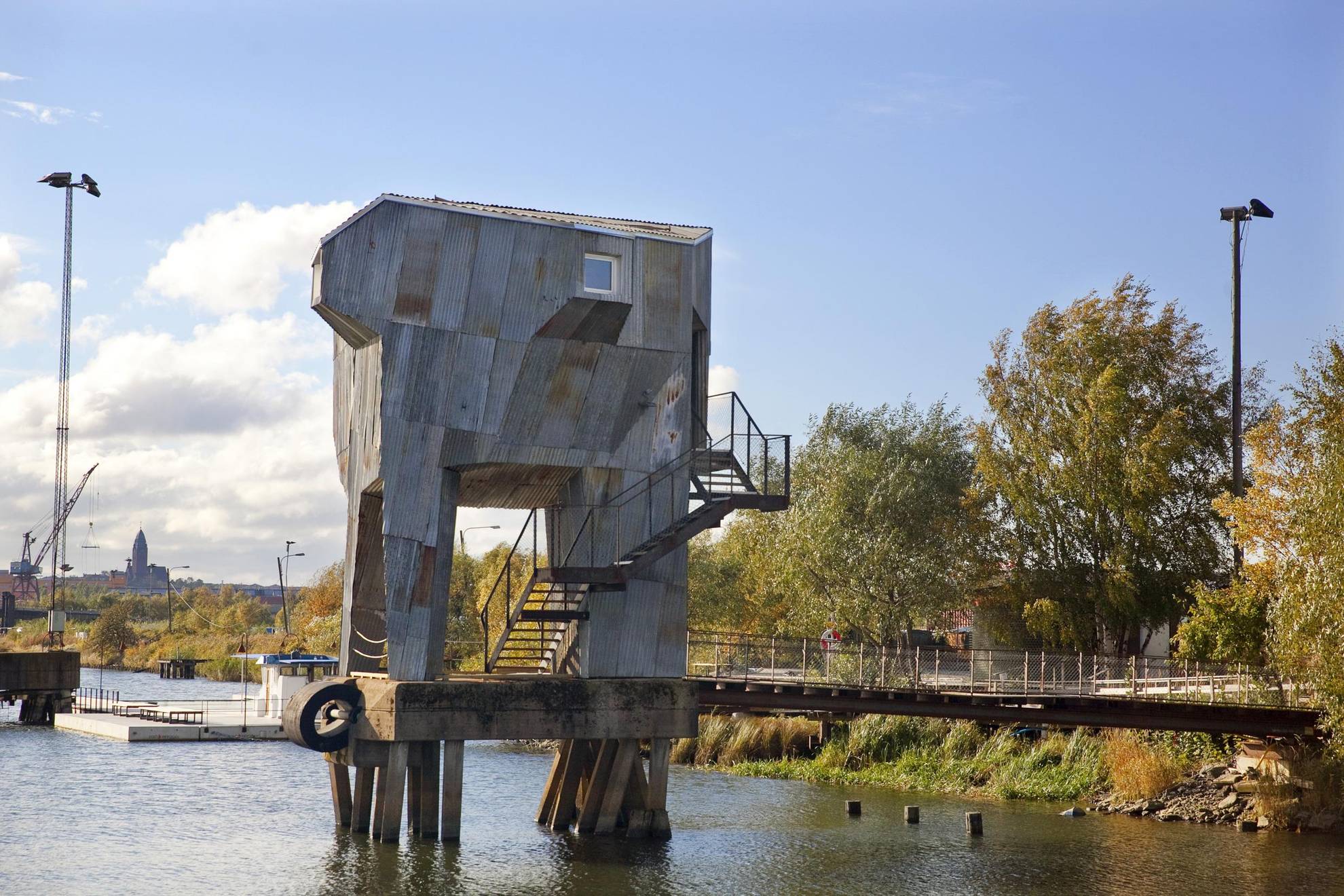 Tall sauna in gray made of recycables, standing on a platform above the water in Frihamnen, Gothenburg.