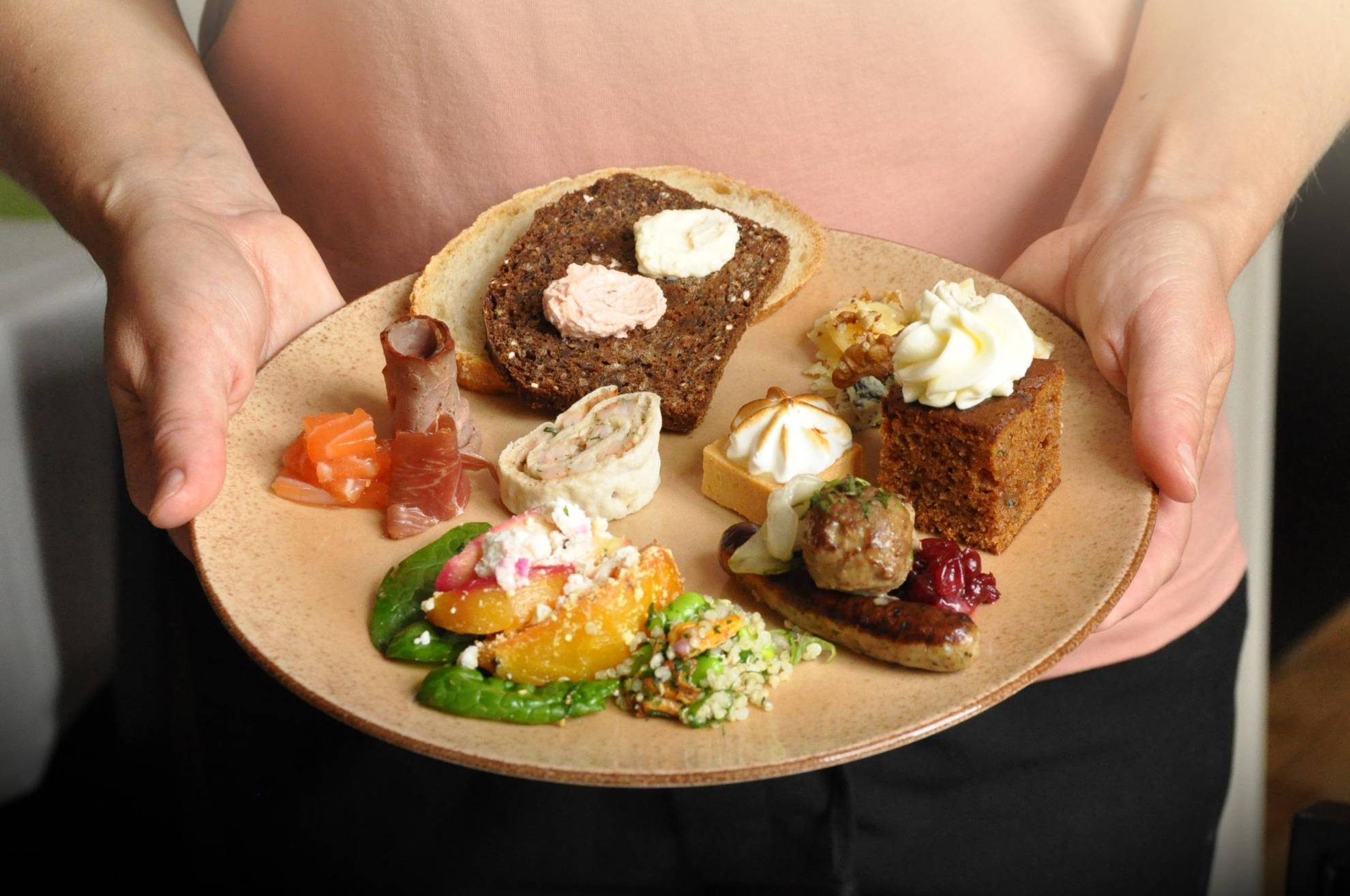 Eine Person hält einen Teller mit verschiedenen Gerichten in der Hand.