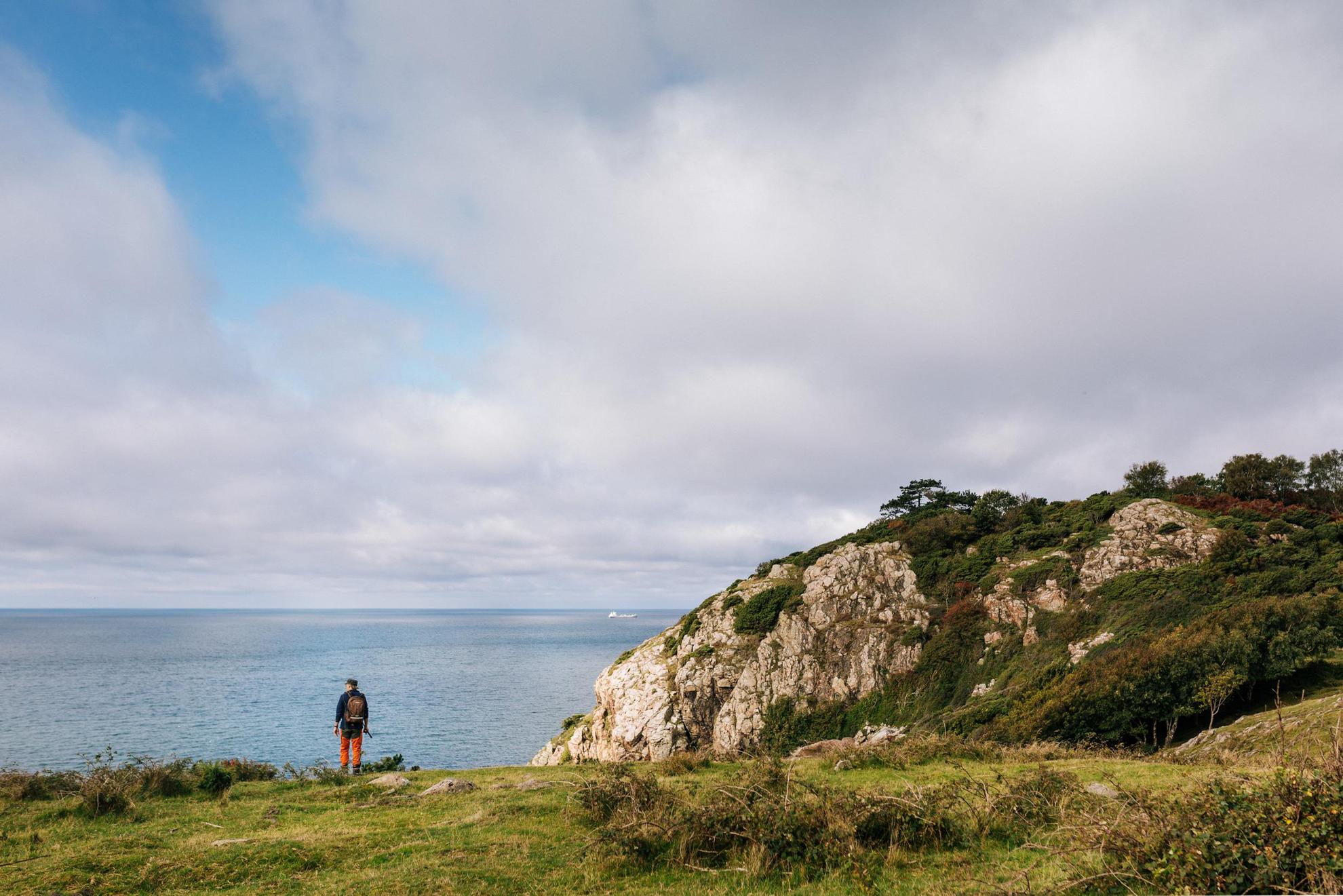Eine Person steht an den Klippen des Naturschutzgebiets Kullaberg und blickt auf das Meer.