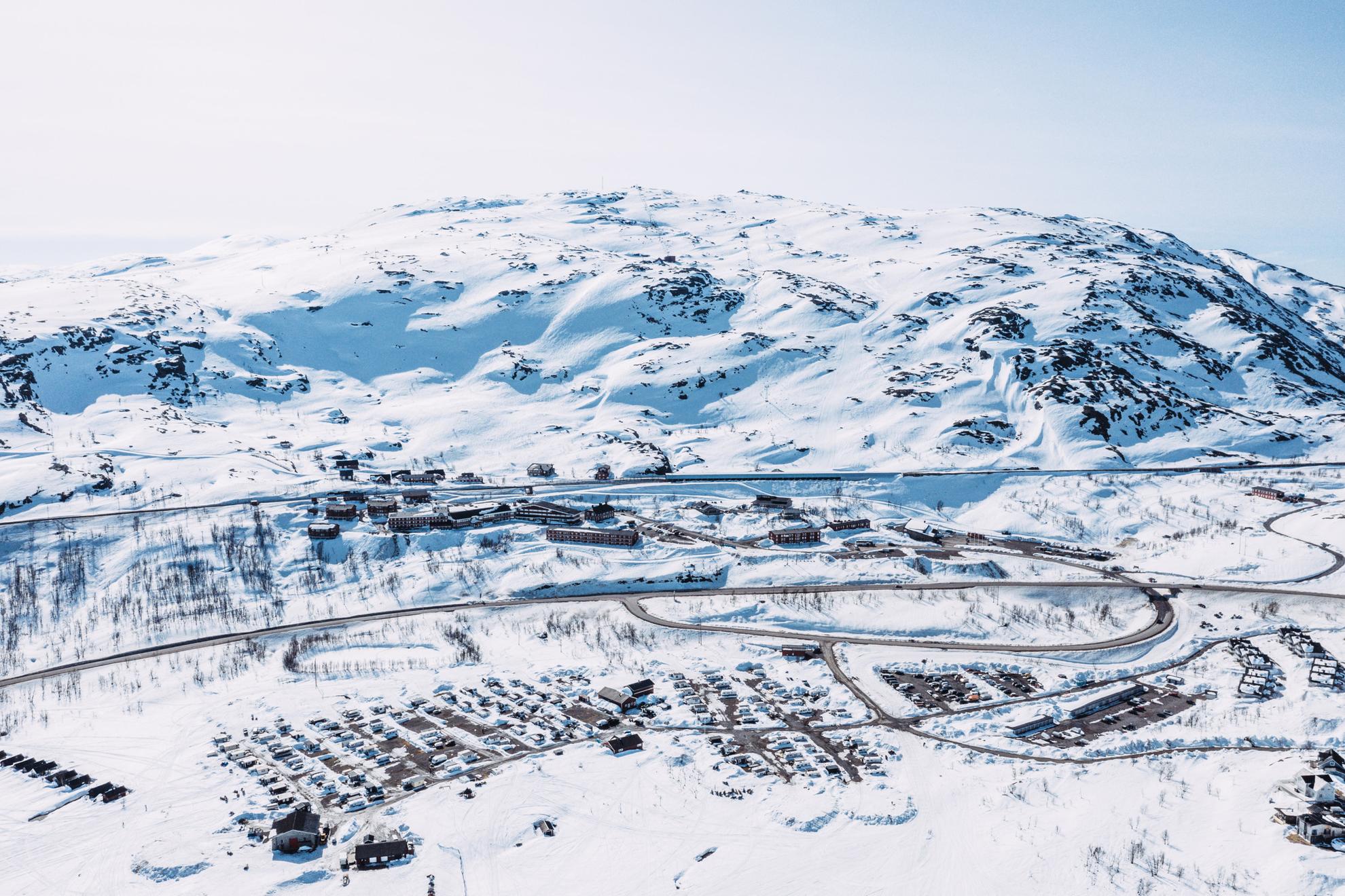 Eine Luftaufnahme eines Campingplatzes, der im Winter an einem Berg liegt.