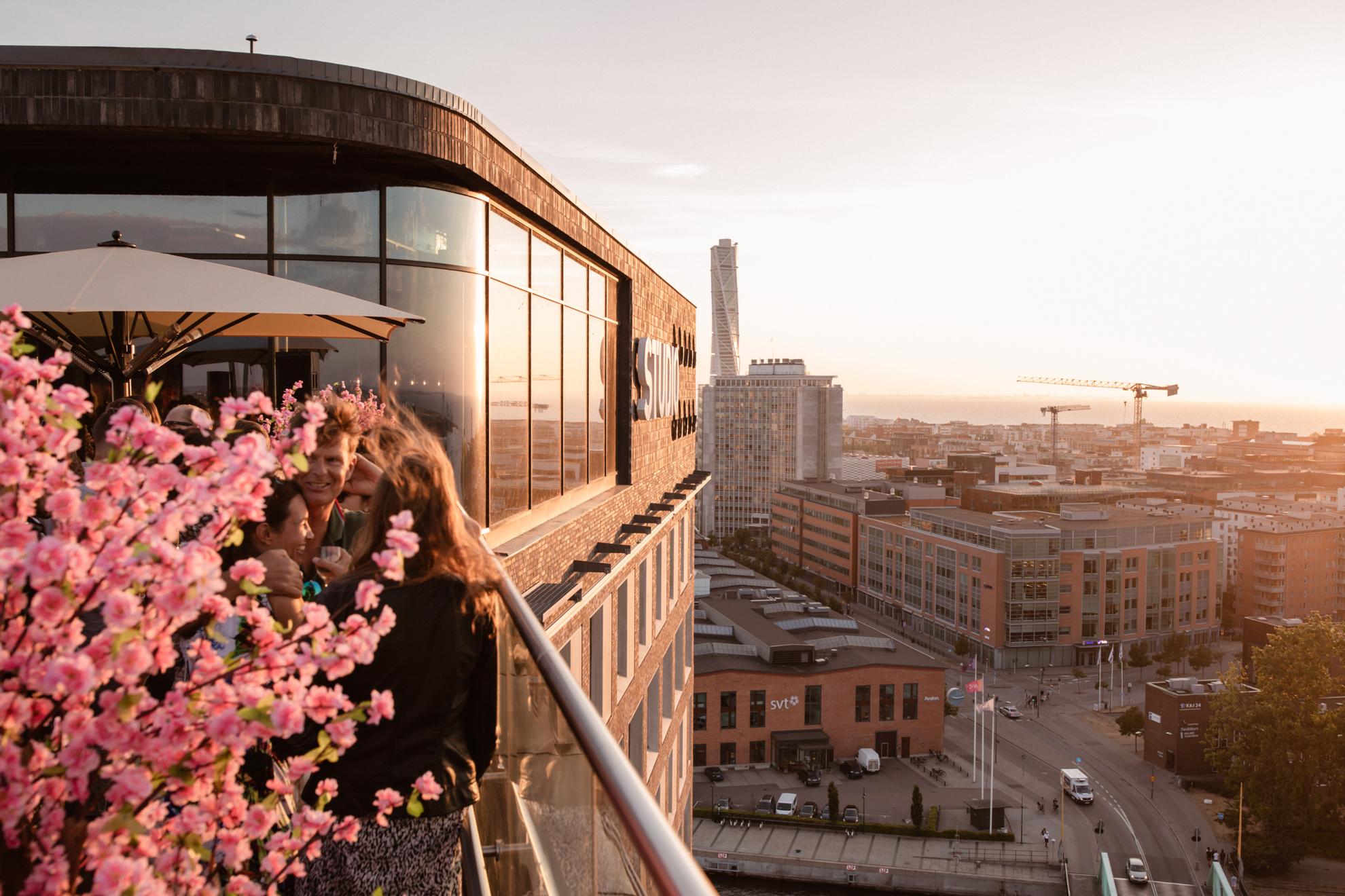 Leute trinken Cocktails auf einer Dachterrassenbar mit Blick über Malmö.