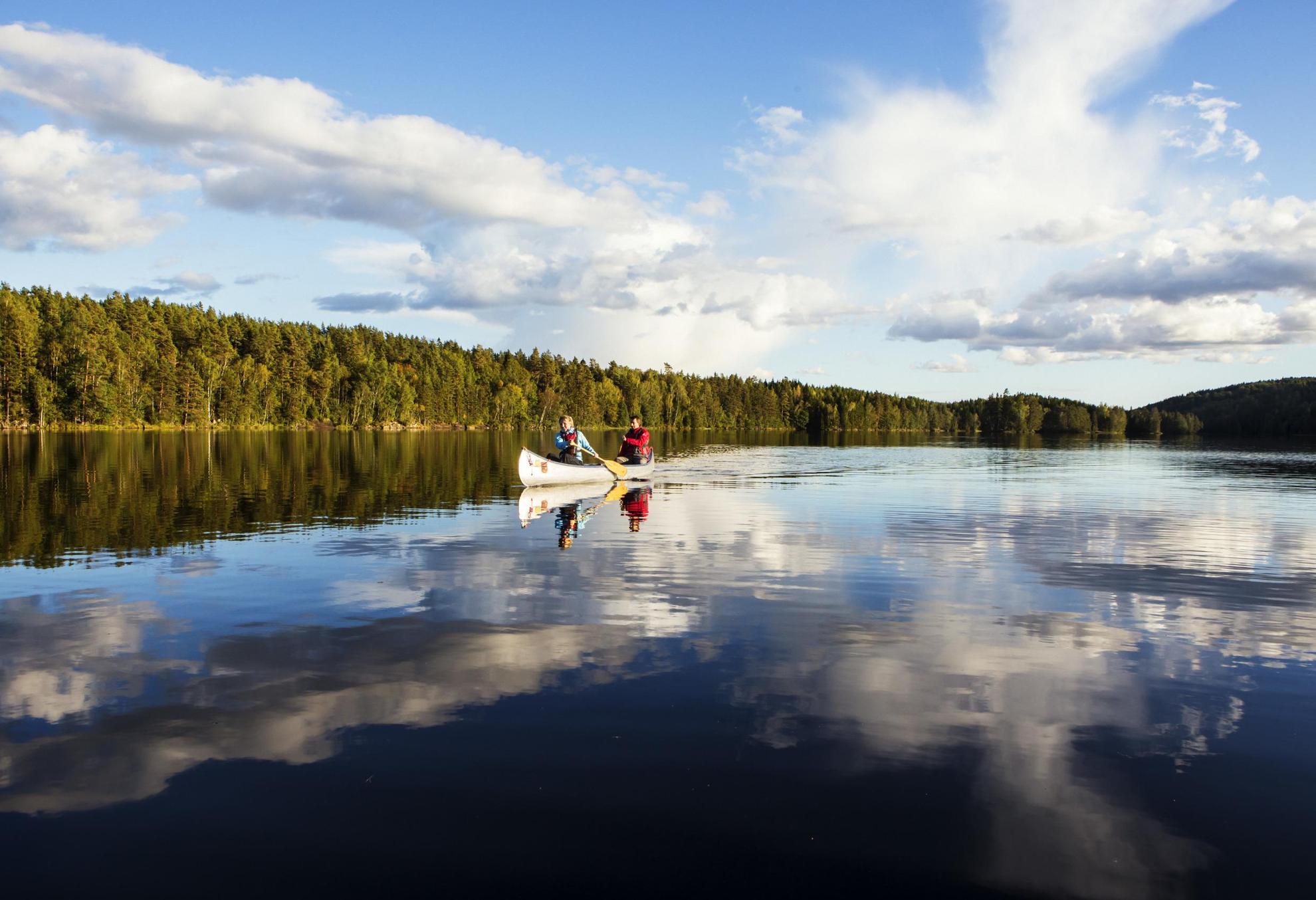 In Dalsland paddeln Personen mit ihrem Kanu über den See.