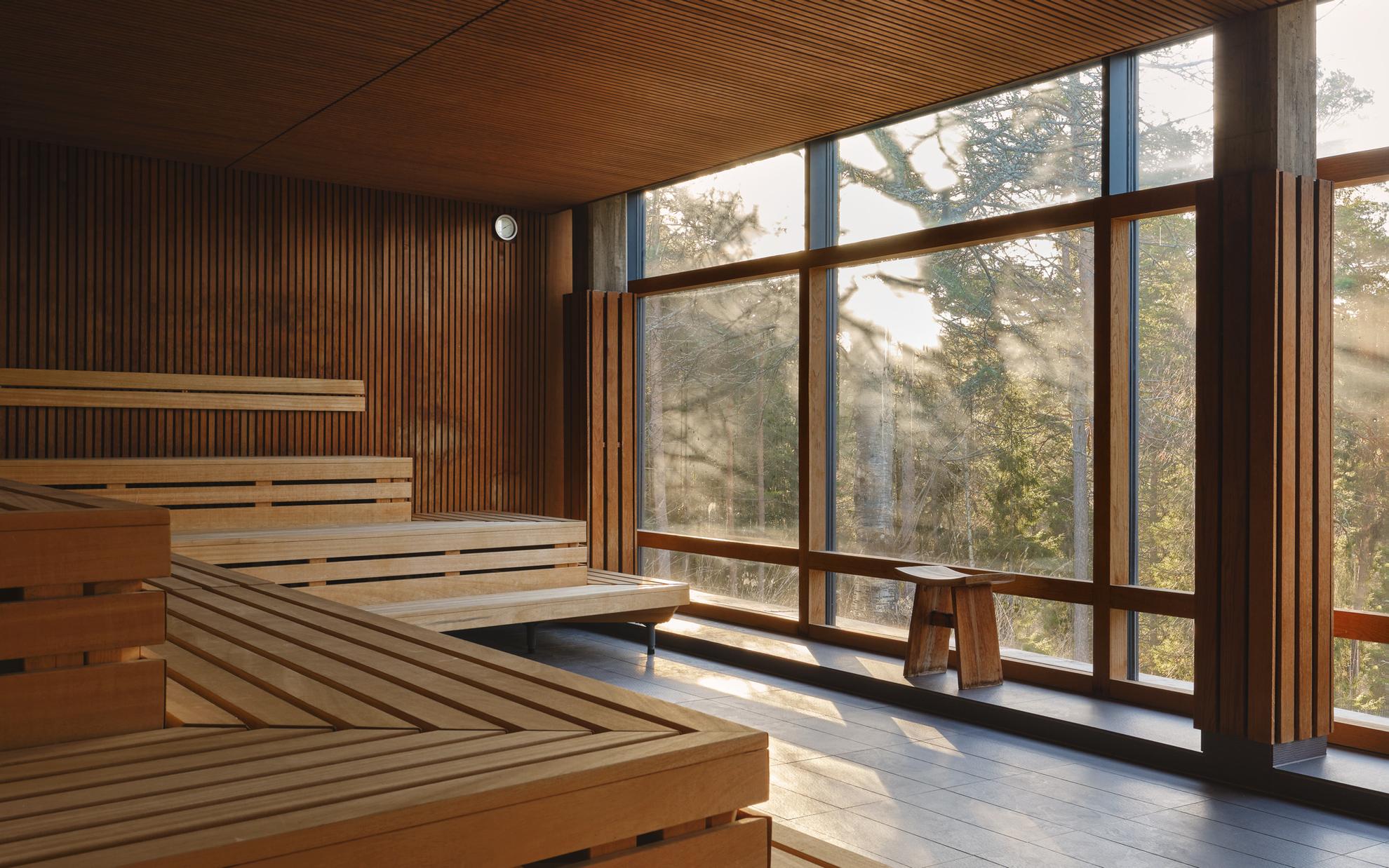 Eine Trockensauna aus Holz mit großen Panoramafenstern mit Blick auf den Wald.