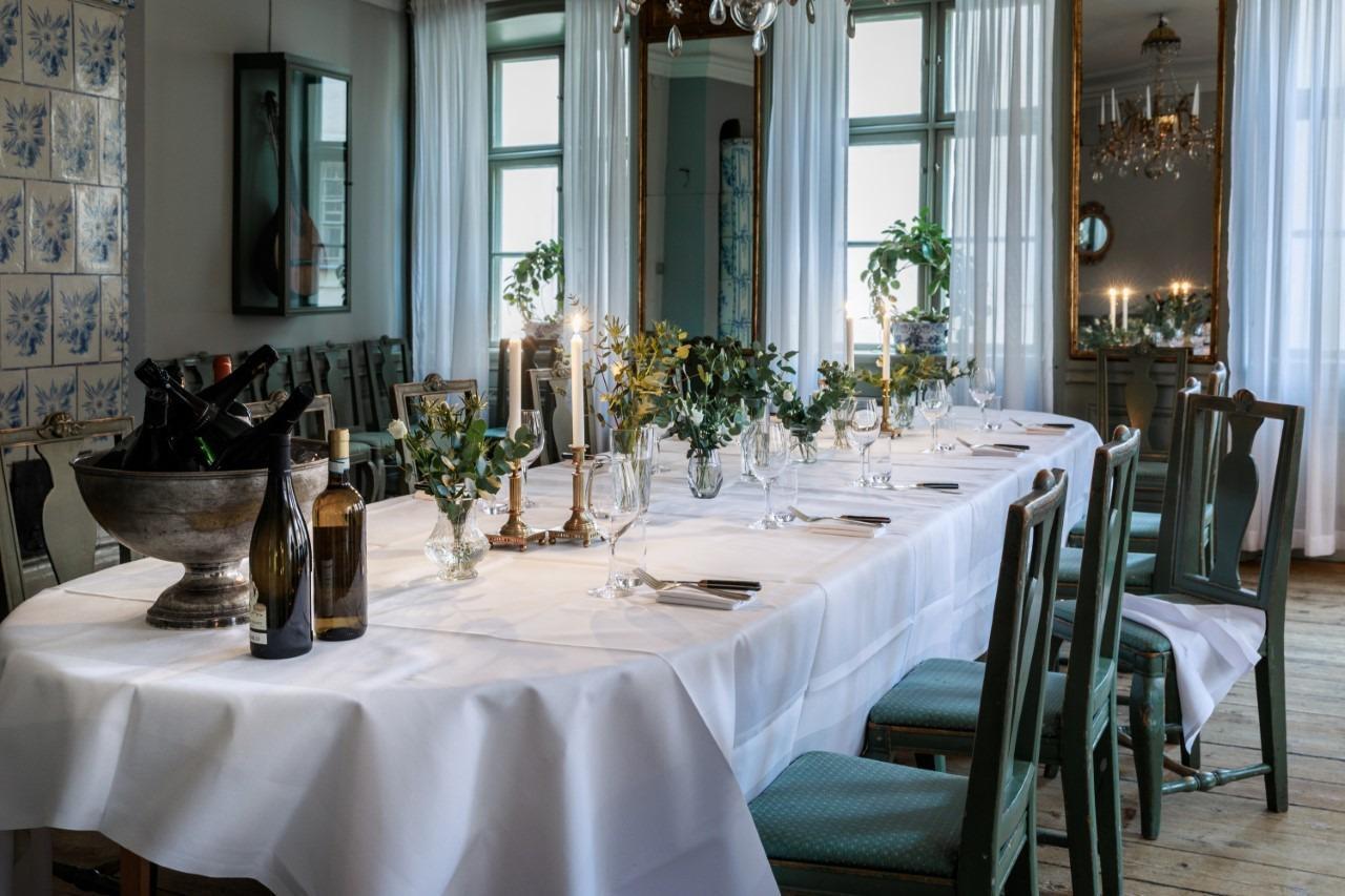 Ein gedeckter Tisch mit einem weißen Tuch, Besteck, Gläsern und Tellern im Den Gyldene Freden Restaurant in Stockholm.