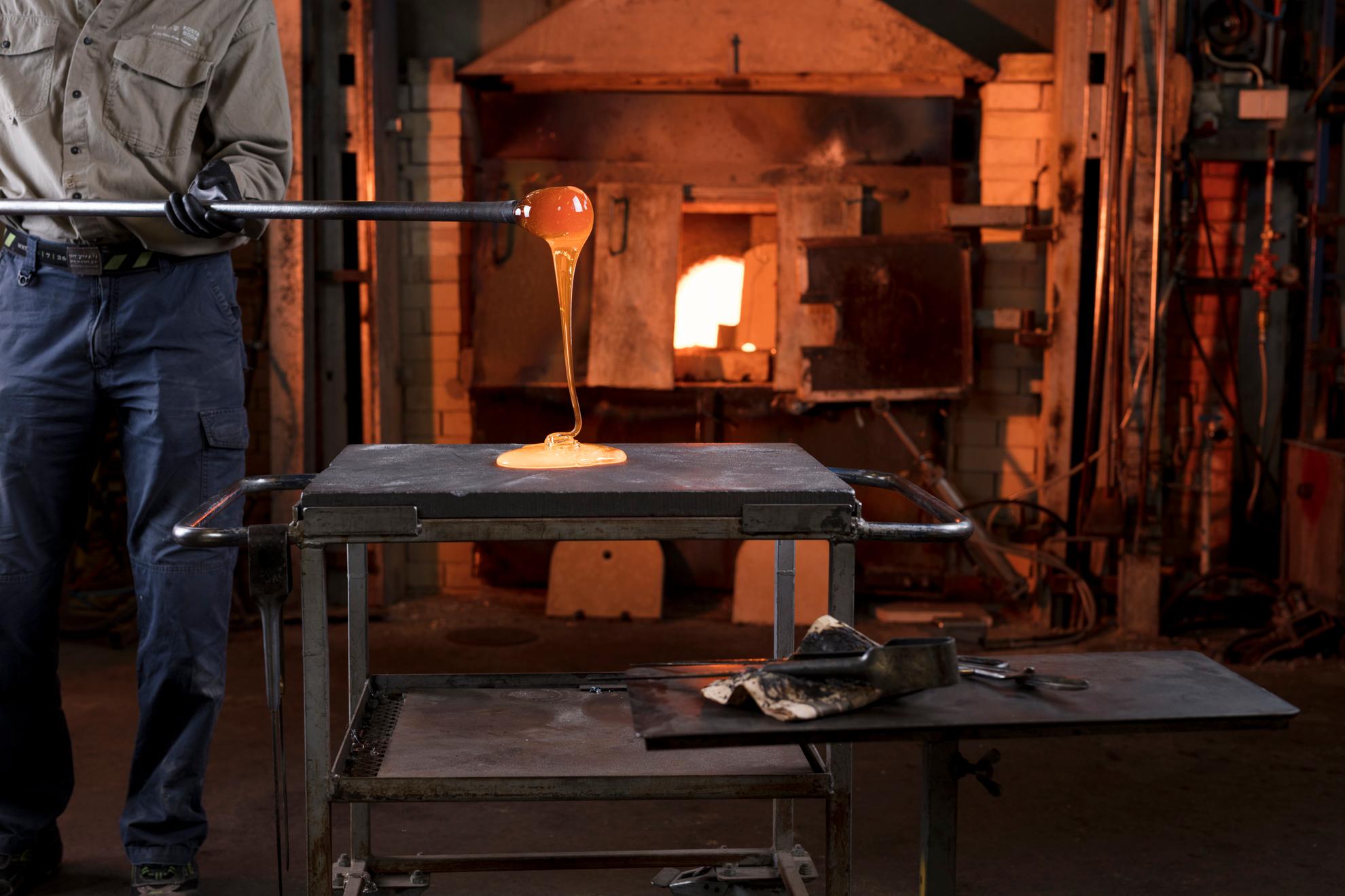 Eine Person arbeitet mit geschmolzenem Glas vor einem Ofen im Glasriket in Smaland..