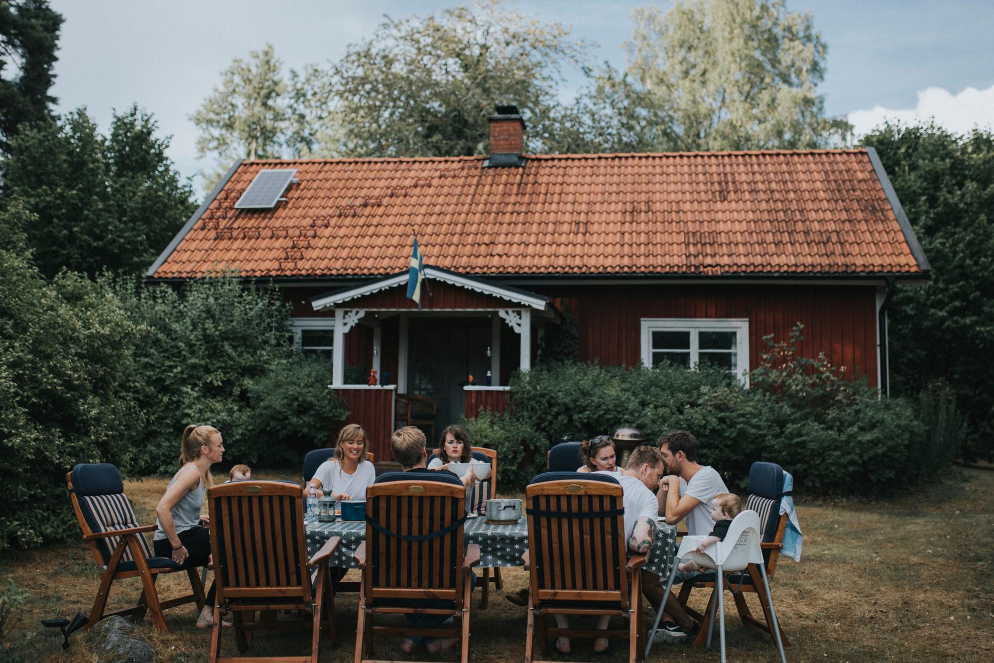 Eine Familie sitzt im Garten an einem großen Gartentisch und isst Abendessen zusammen.