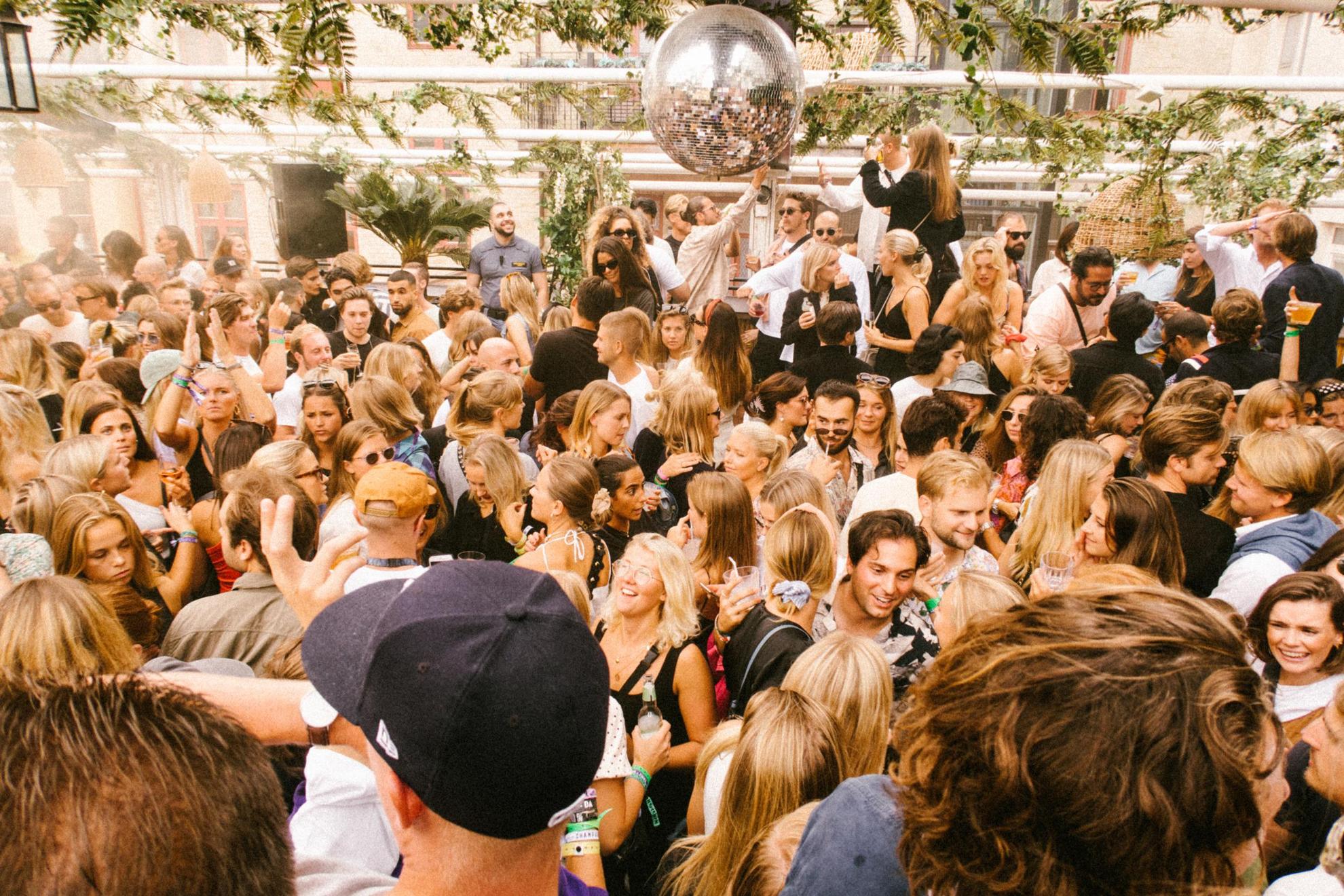 Menschen tanzen im Sommer in einem Club auf einer Dachterrasse.