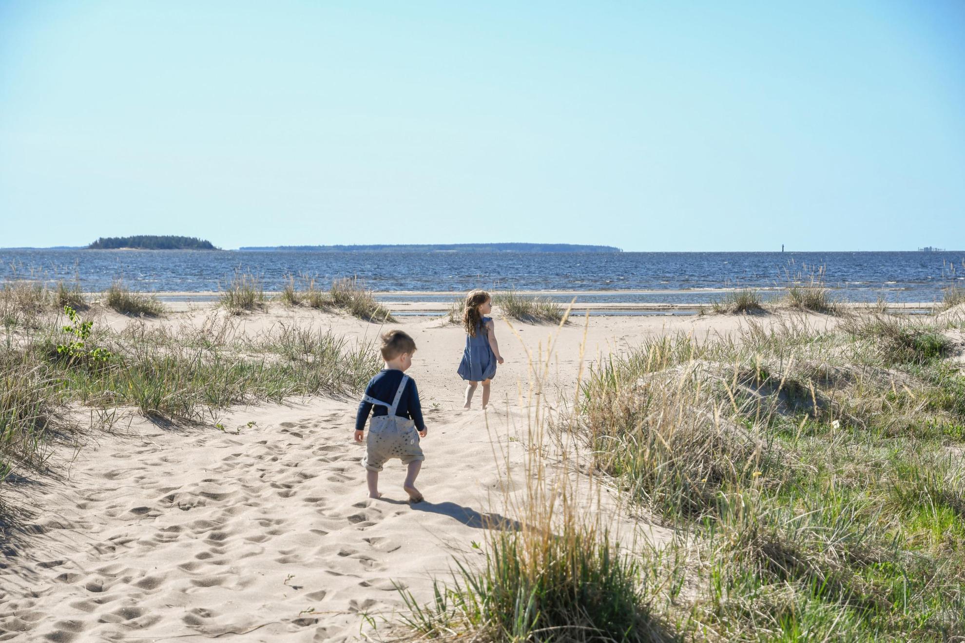 Zwei Kinder laufen an einem Strand im Sommer.