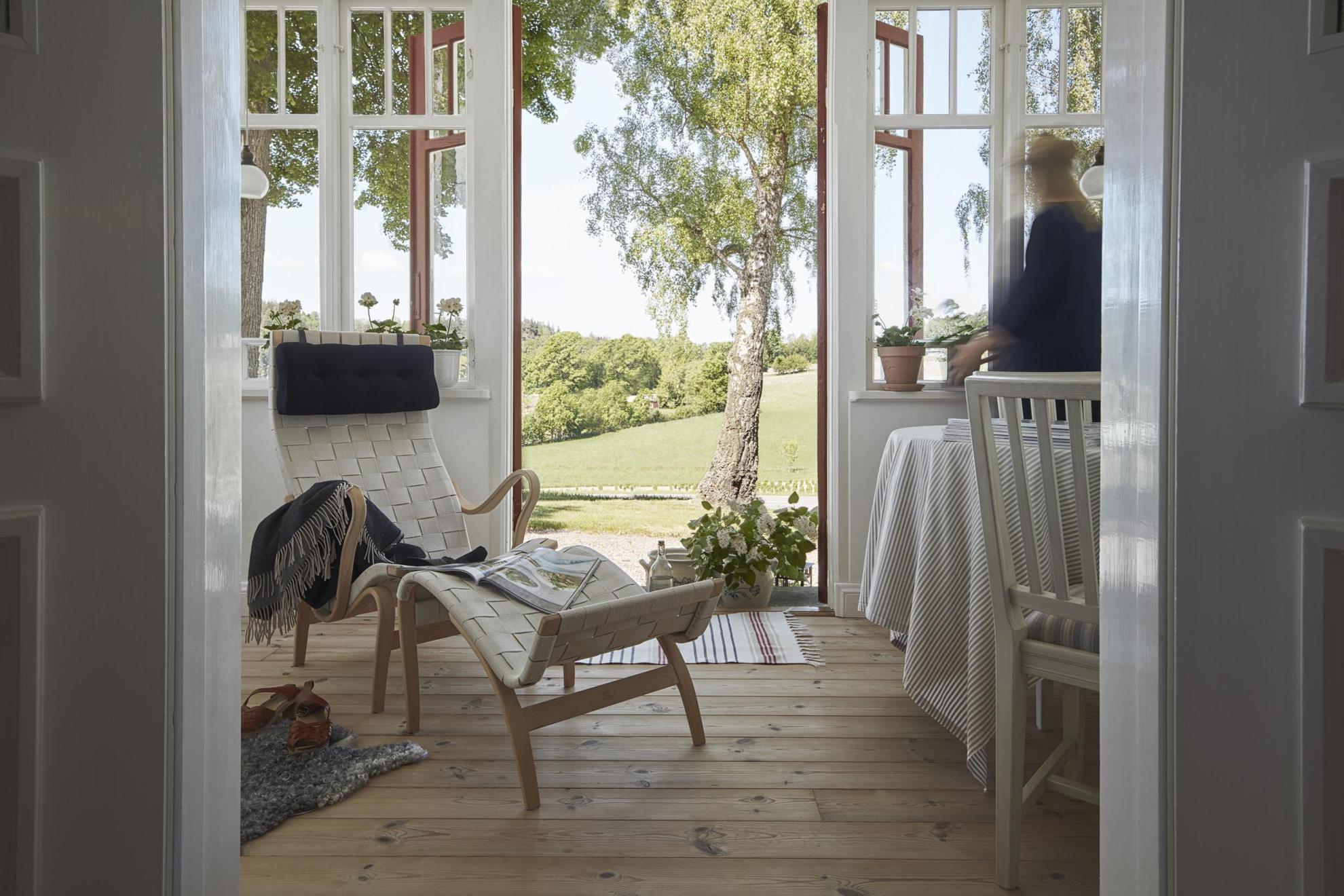 Ein weißer Relaxsessel von Bruno Mathsson in einem Wohnzimmer mit Türen zu einem grünen Garten.