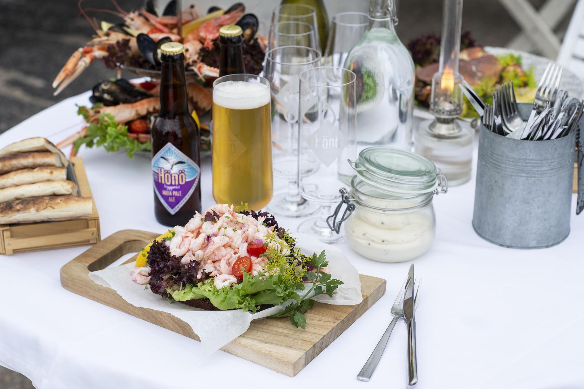 A set table with a seafood sandwich, seafood platters and beer from Hönö brewery.