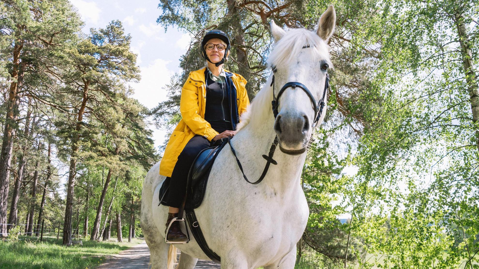 Eine Frau sitzt auf einem weißen Pferd.