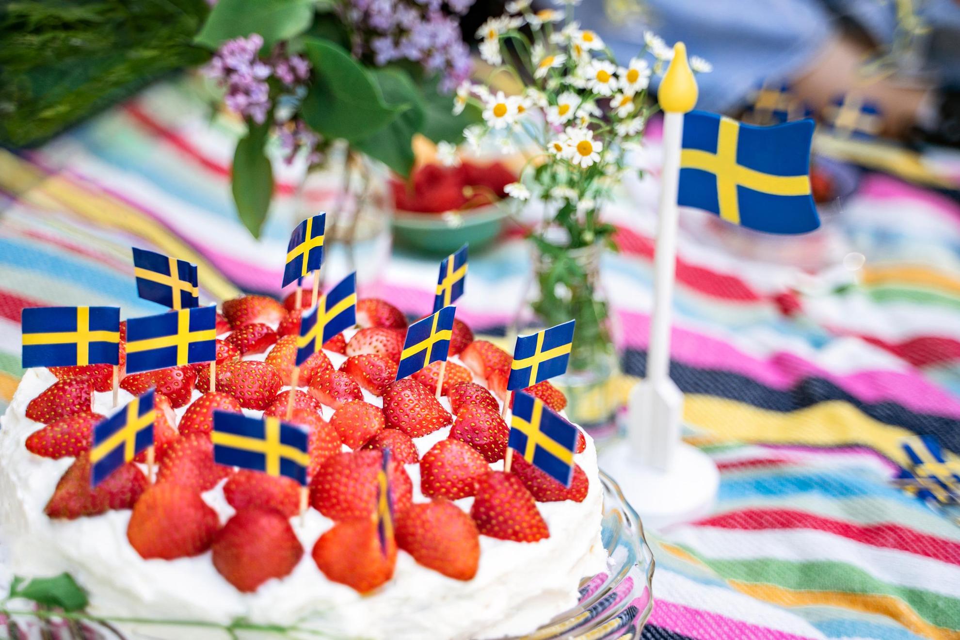 Ein Erdbeerkuchen, der mit vielen kleinen schwedischen Flaggen verziert ist.