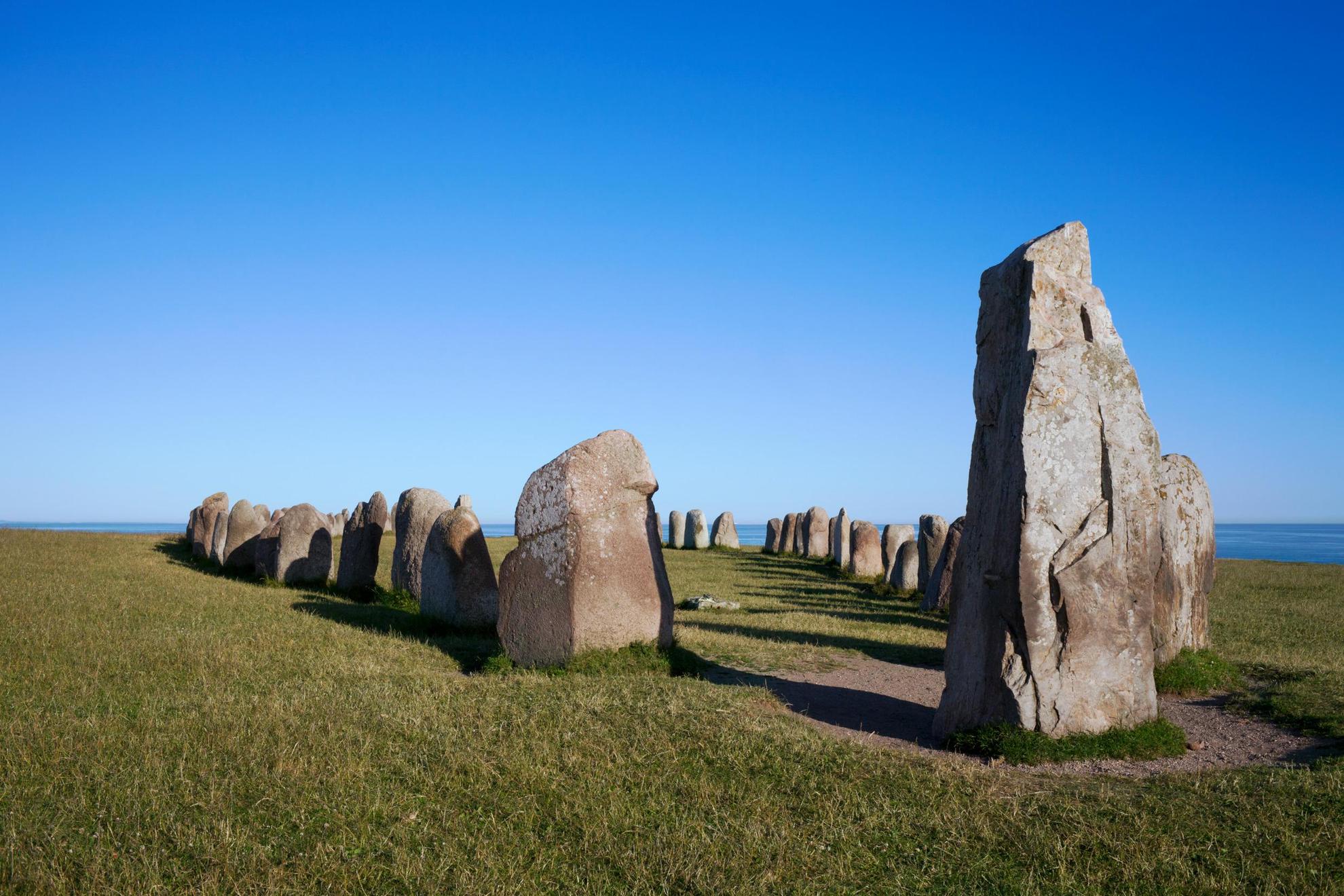 The Ale Stones stand on a field with the ocean in the background.