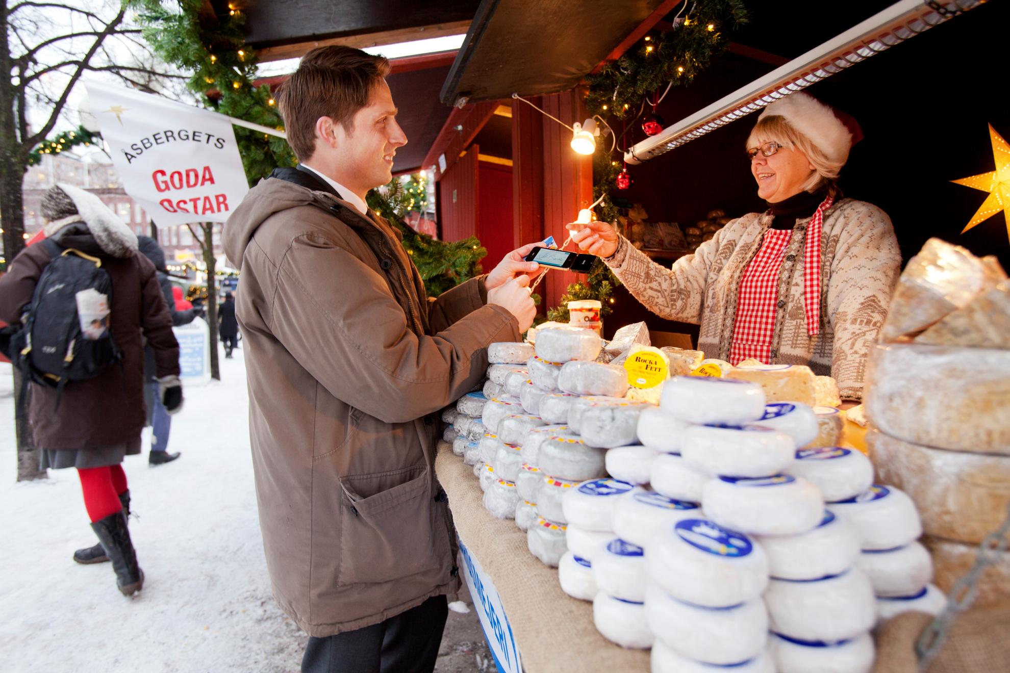 Ein Mann zahlt an einem Weihnachtsmarktstand in Schweden mit der Karte.