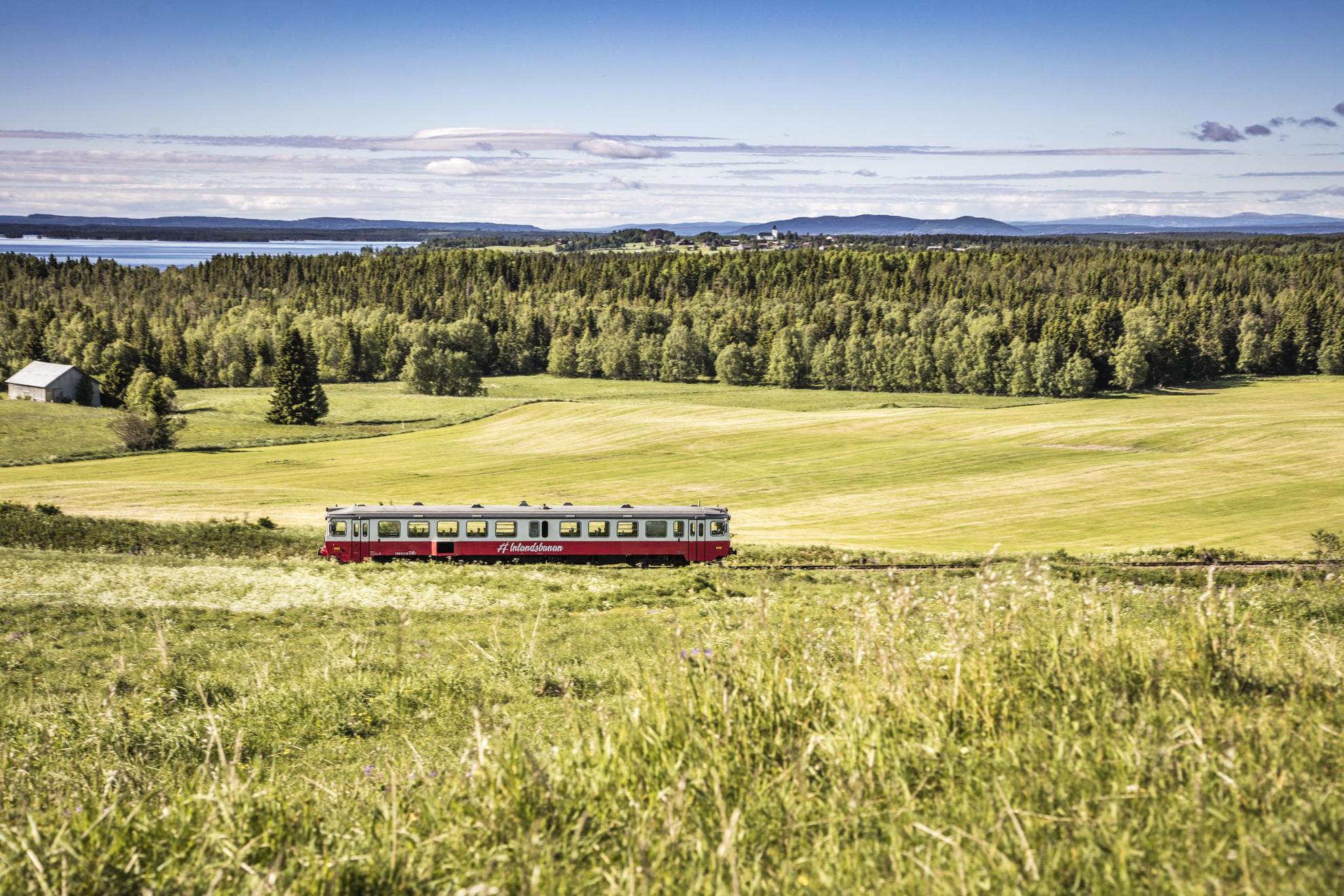 Die Inlandsbanan fährt durch die schwedische Landschaft mit Feldern, Wäldern, Wasser und Bergen.