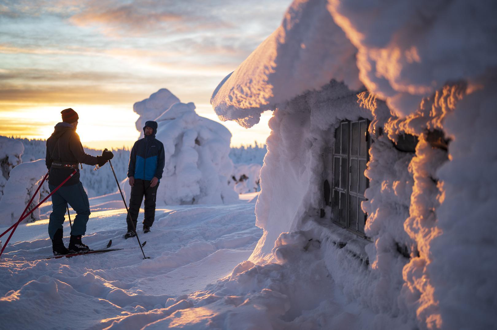 Zwei Ski-Langläufer an einer Hütte in Winterlandschaft..