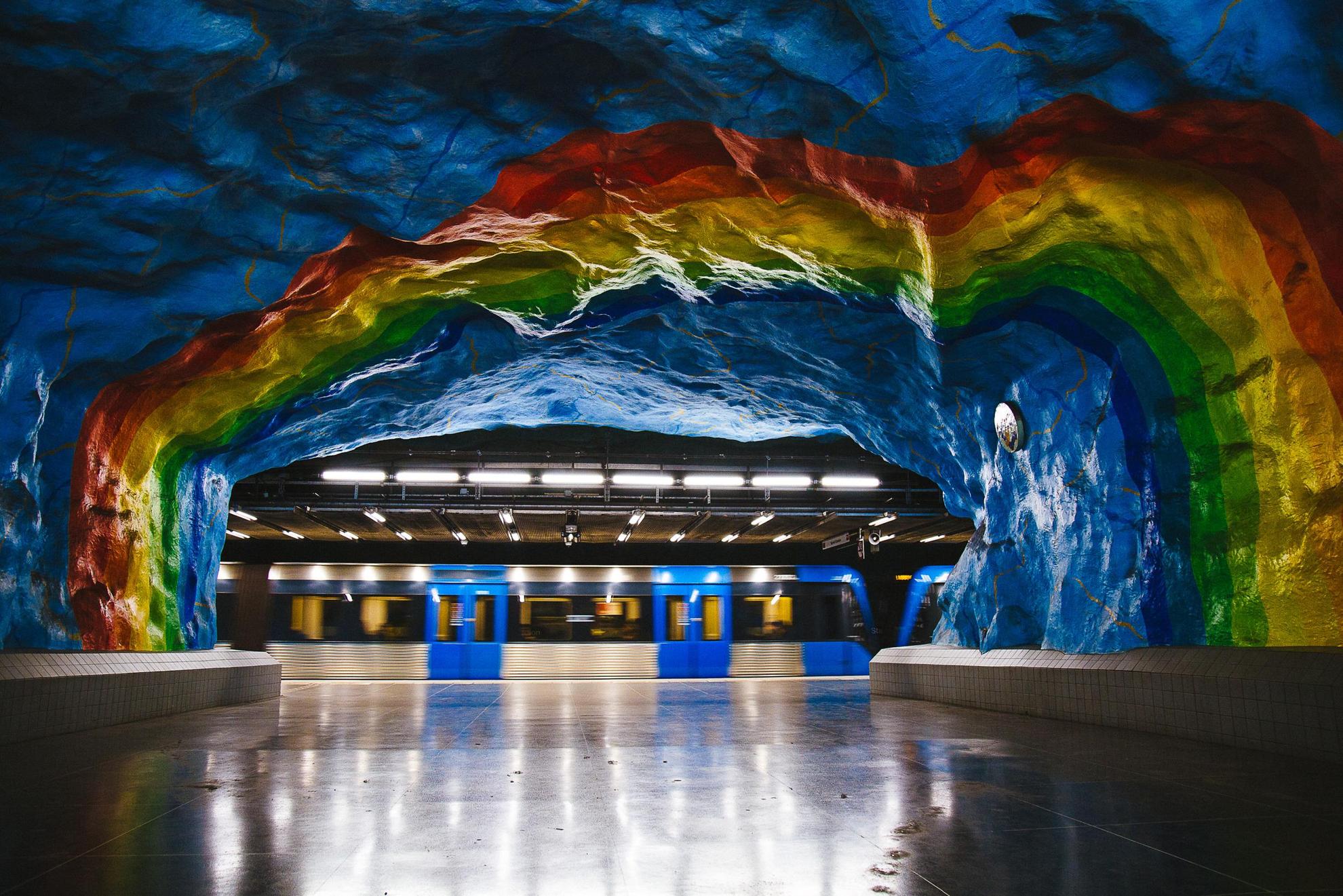Die Wände einer Haltestelle der Stockholmer U-Bahn sind bunt verziehrt und ähneln einem Regenbogen.