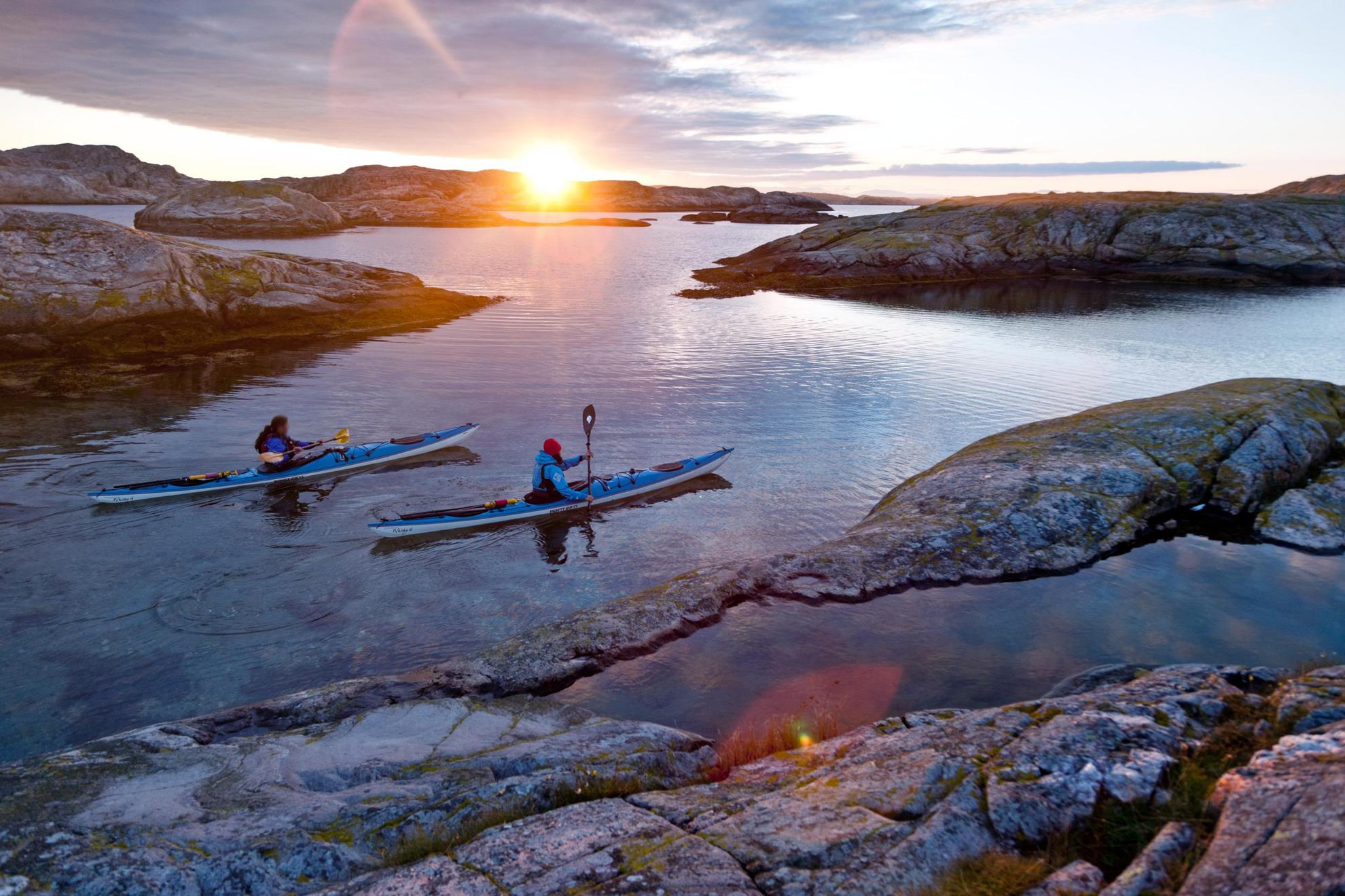 Bei Sonnenuntergang fahren zwei Kajaks an den Inseln der Küste von Bohuslän vorbei.