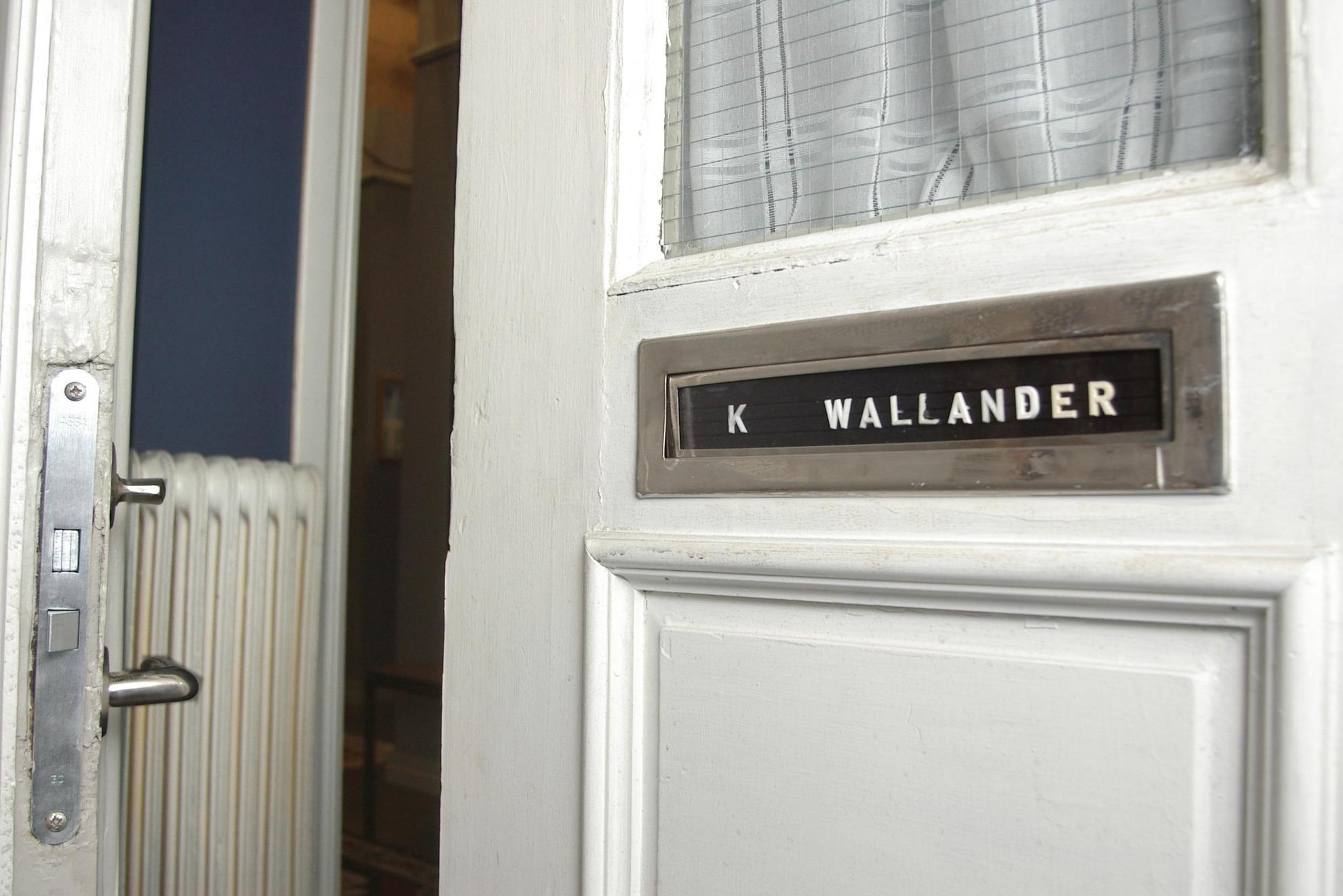 A door is half opened. It has 'K Wallander' written on it.
