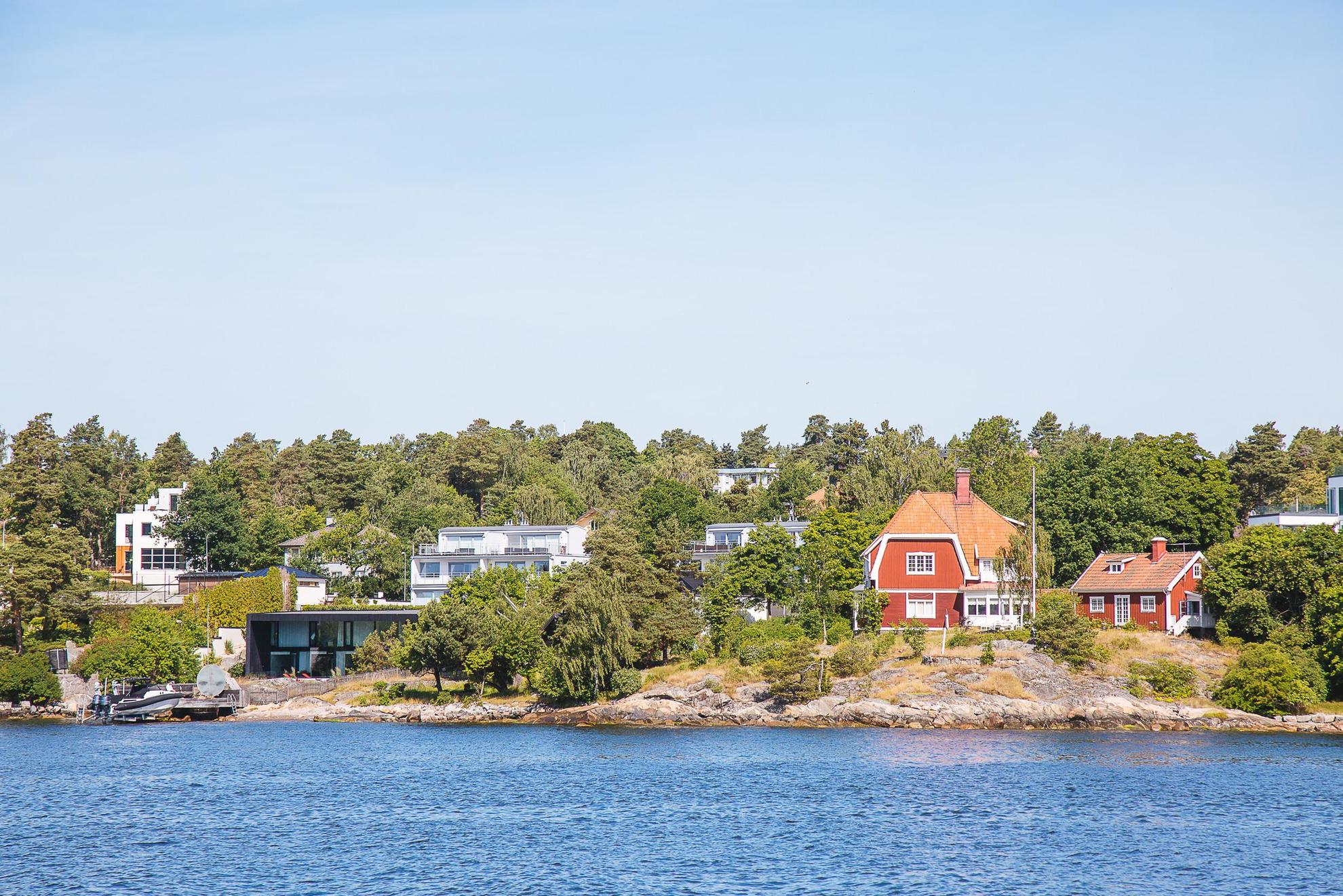 Ein modernes und ein klassich rotes Schwedenhaus stehen am Ufer einer Insel im Stockholmer Schärengarten.